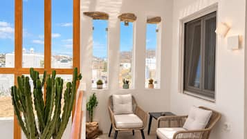 A balcony with wicker furniture, a cactus plant, and a view of a coastal town.
