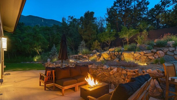 A patio with a stone wall, a fire pit, and outdoor furniture. - Hot tub, Outdoor dining, BBQ Grill, Fire pit & Gym (Colorado Springs)