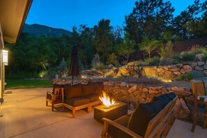 Eine Terrasse mit Steinmauer, Feuerstelle und Gartenmöbeln.