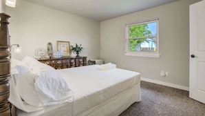 Een slaapkamer met een bed, een dressoir en een raam met uitzicht.