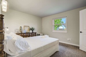 Een slaapkamer met een bed, een dressoir en een raam met uitzicht.
