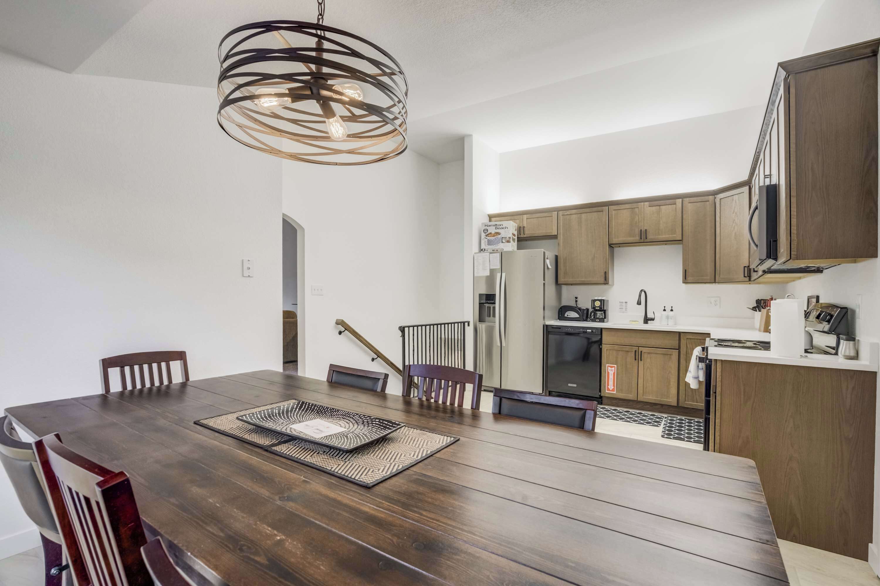 A modern kitchen with wooden cabinets, a stainless steel refrigerator, and a built-in oven.