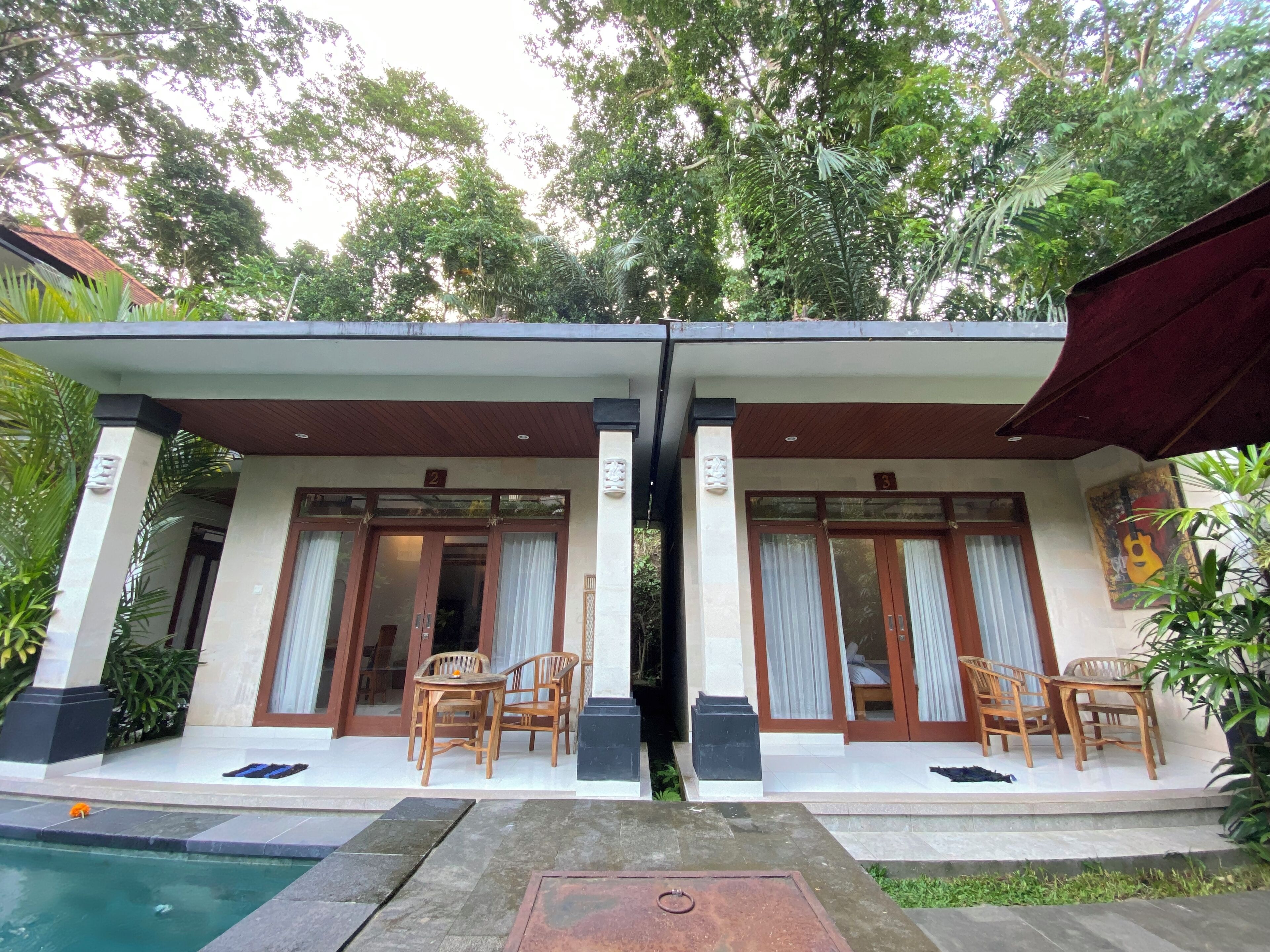 A two-story building with a covered patio area, numbered doors, and outdoor seating.
