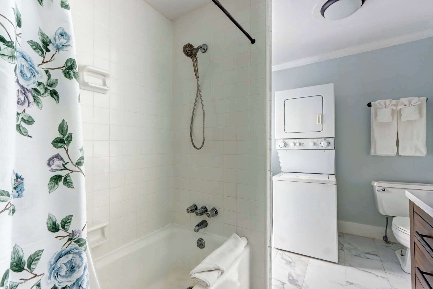 A bathroom with a shower, a toilet, a sink, and a built-in washing machine.