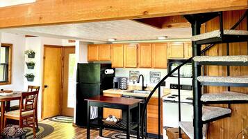 Um amplo loft com teto alto, vigas de madeira, área de cozinha e escada em espiral.