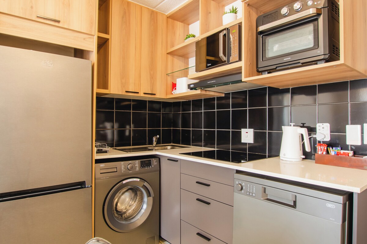 Une cuisine compacte équipée d’un lave-linge, d’un four à micro-ondes et d’un lave-vaisselle.