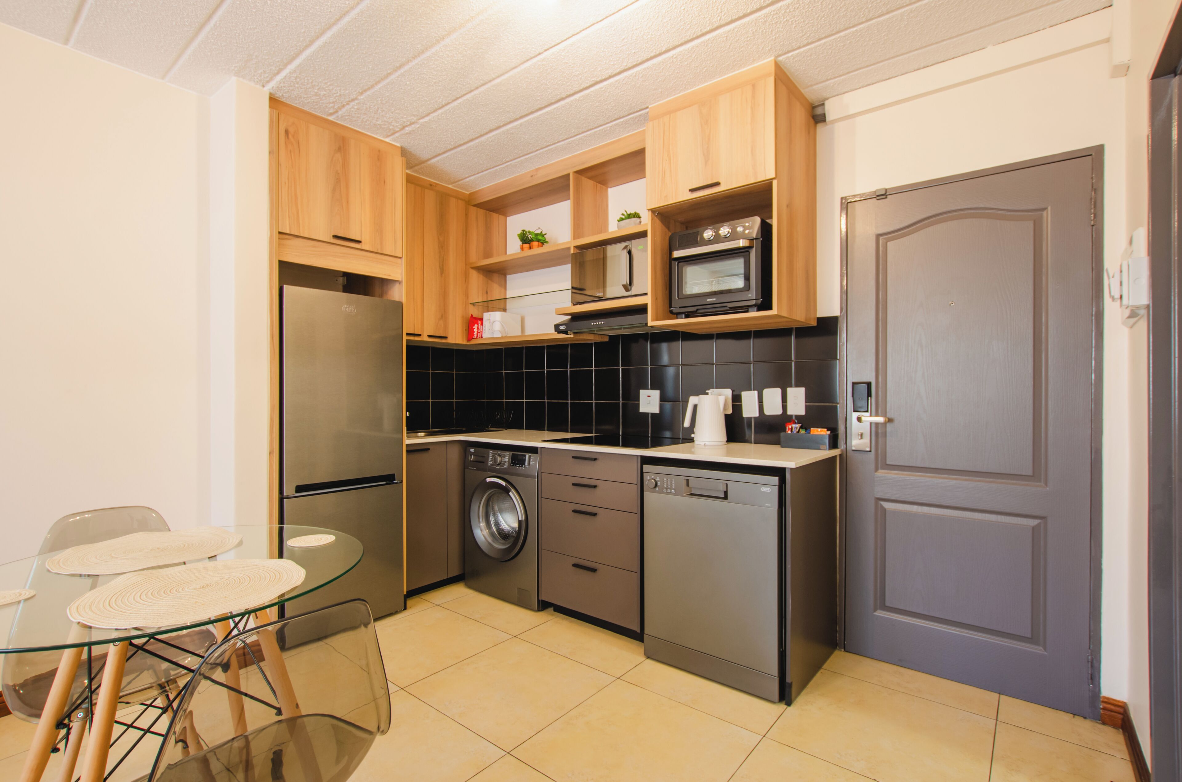 A compact kitchen with a refrigerator, oven, microwave, washing machine, and dishwasher.