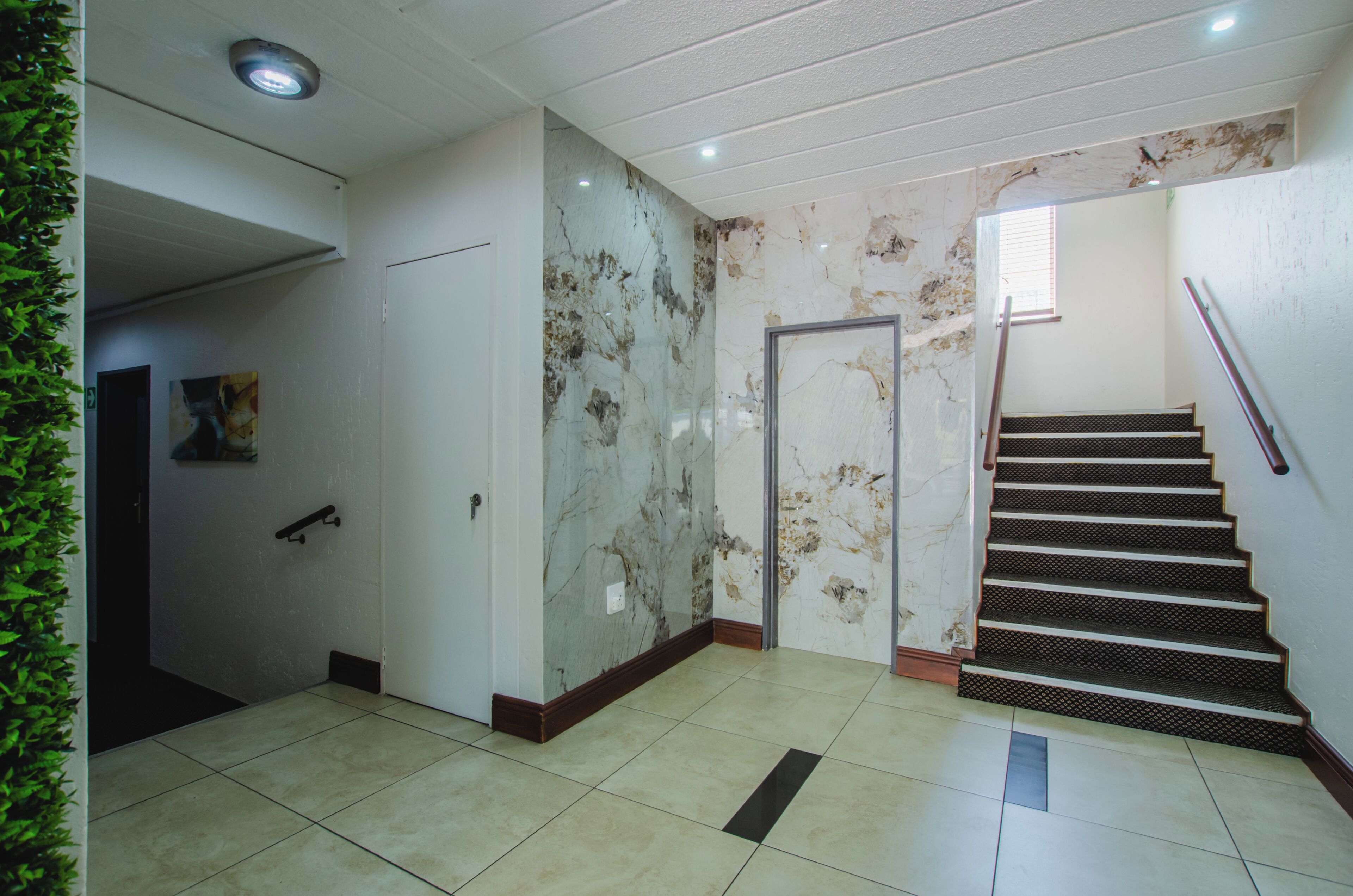 A staircase with a handrail, a door, and a wall with a marble-like pattern.