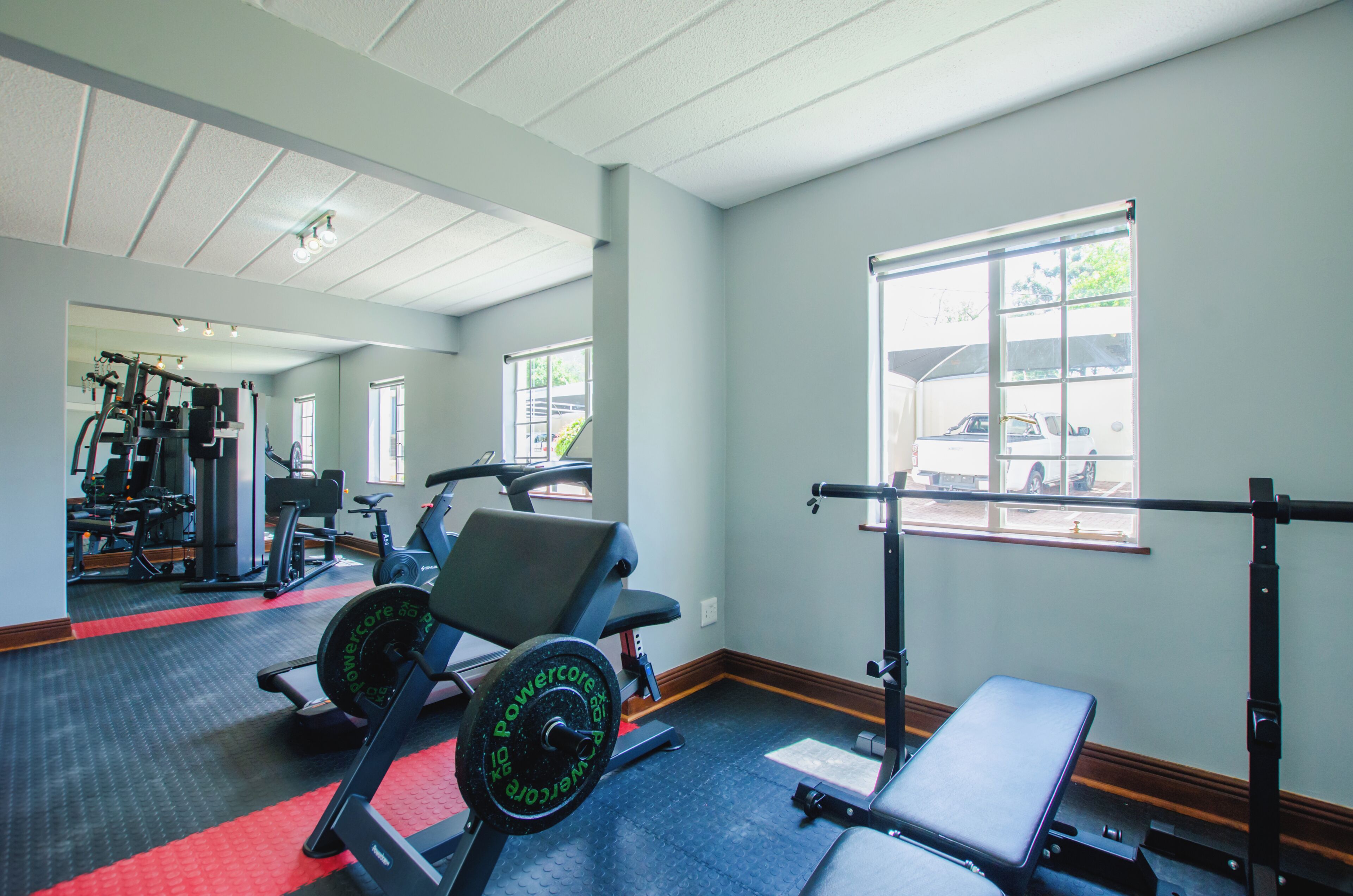 A gym with exercise equipment, a bench, and a window with a view of the outside.