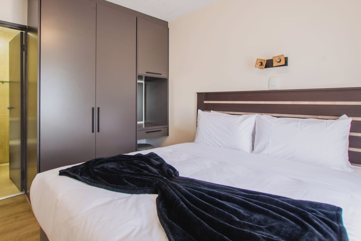 Habitación de hotel con cama, bata, armario y espejo.