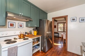 A kitchen with teal cabinets, stainless steel appliances, and a wooden countertop.