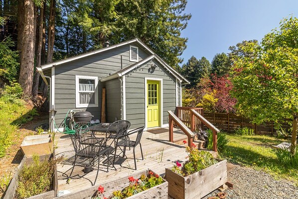 A small house with a porch, a table and chairs, and a bright yellow door.