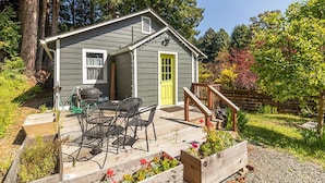 Ein kleines Haus mit Veranda, Tisch und Stühlen und einer leuchtend gelben Tür.