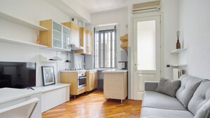 A modern kitchen with wooden cabinets, a built-in oven, and a window. - Lovely 1-bed apt next to the City Centre (Milan)