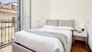 A bedroom with a bed, bedside tables, and a view through a sliding glass door. - Lovely 1-bed apt next to the City Centre (Milan)