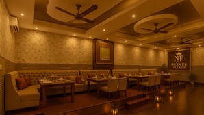 A spacious lounge area with sofas, tables, and ceiling fans. - Nexhub Palace (Gurugram)