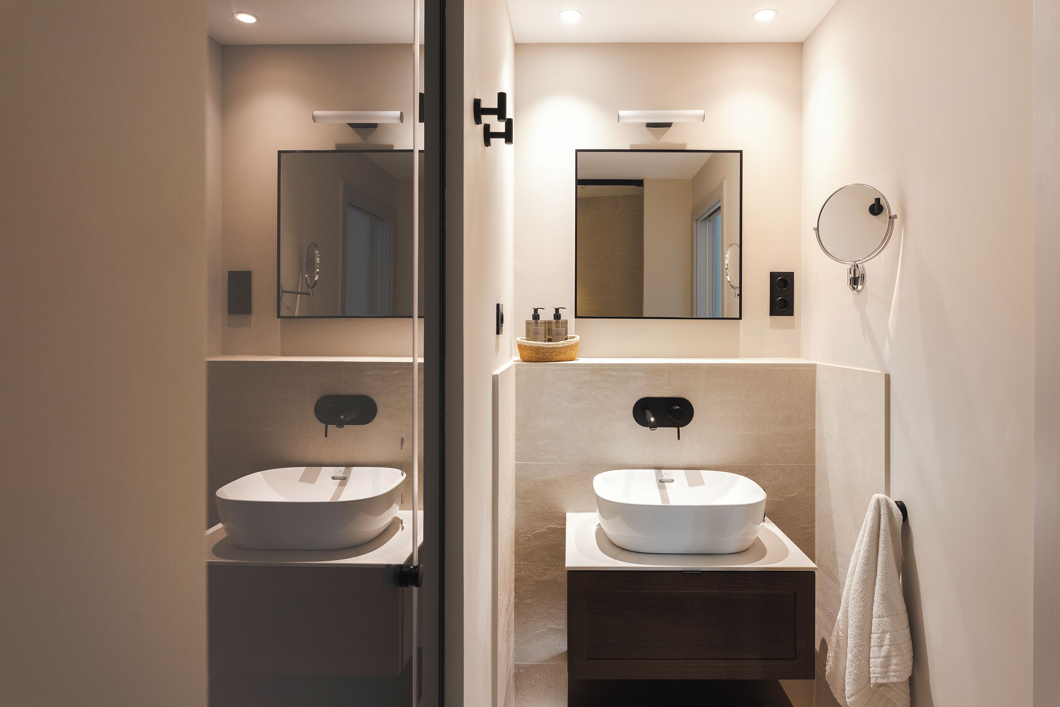 A modern bathroom with two sinks, a mirror, and a towel rack.