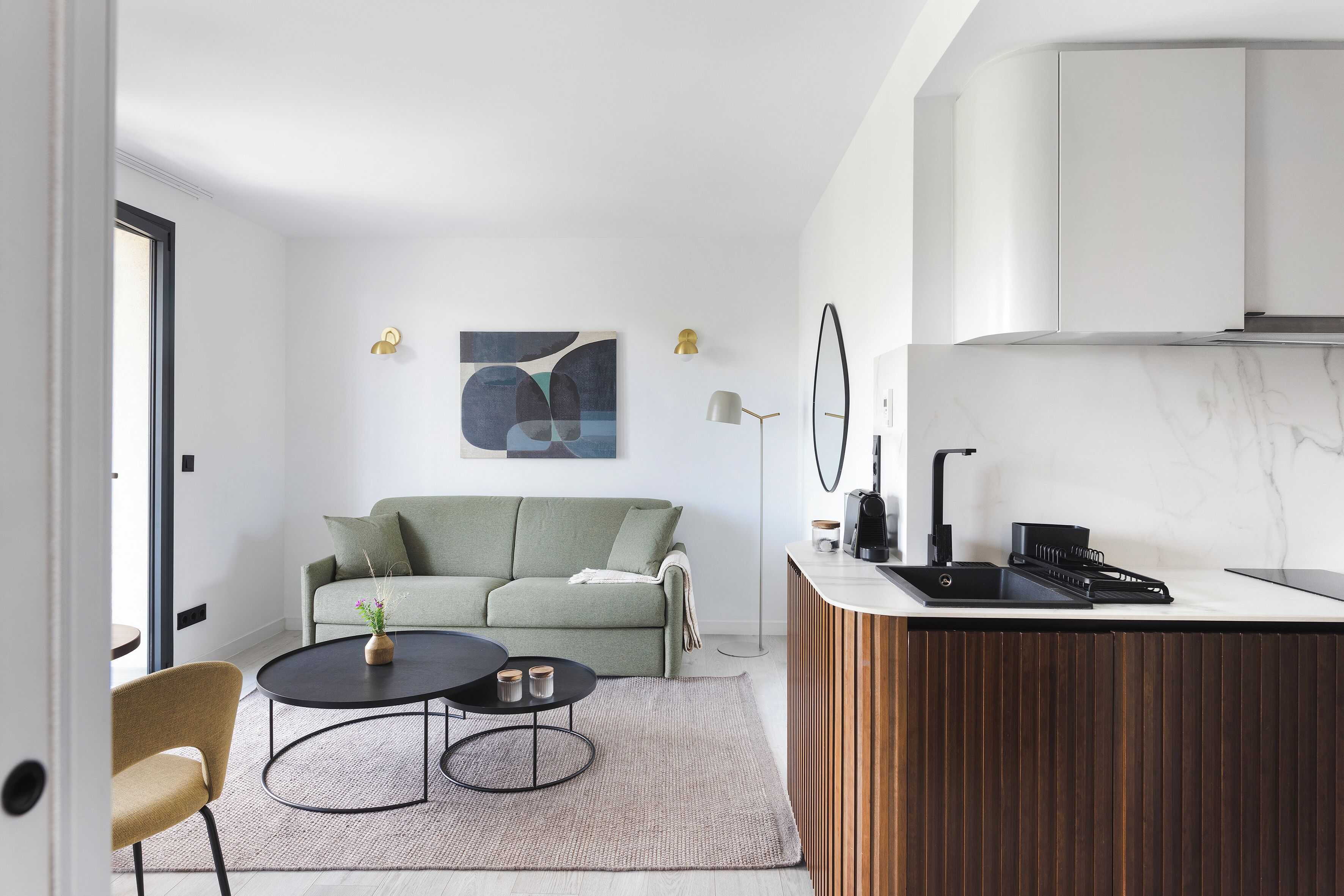 Un espacio habitable moderno con sofá, mesa de centro y cocina, que incluye encimera y armarios.