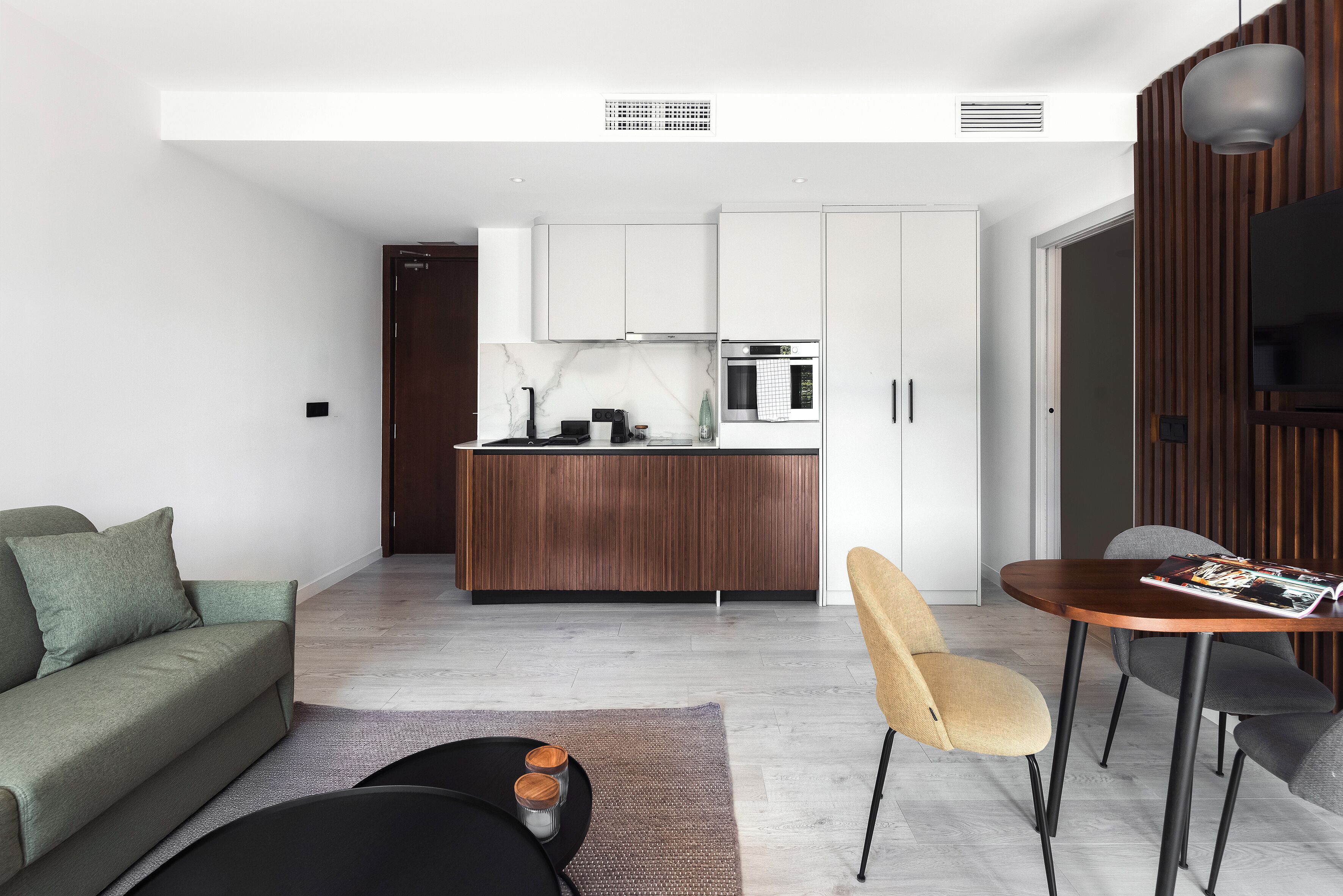 A modern living room with a sofa, coffee table, and a dining area with chairs and a table.