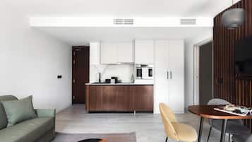 A modern living room with a sofa, coffee table, and a dining area with chairs and a table.