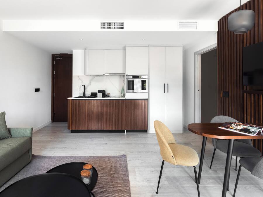 A modern living room with a sofa, coffee table, and a dining area with chairs and a table.