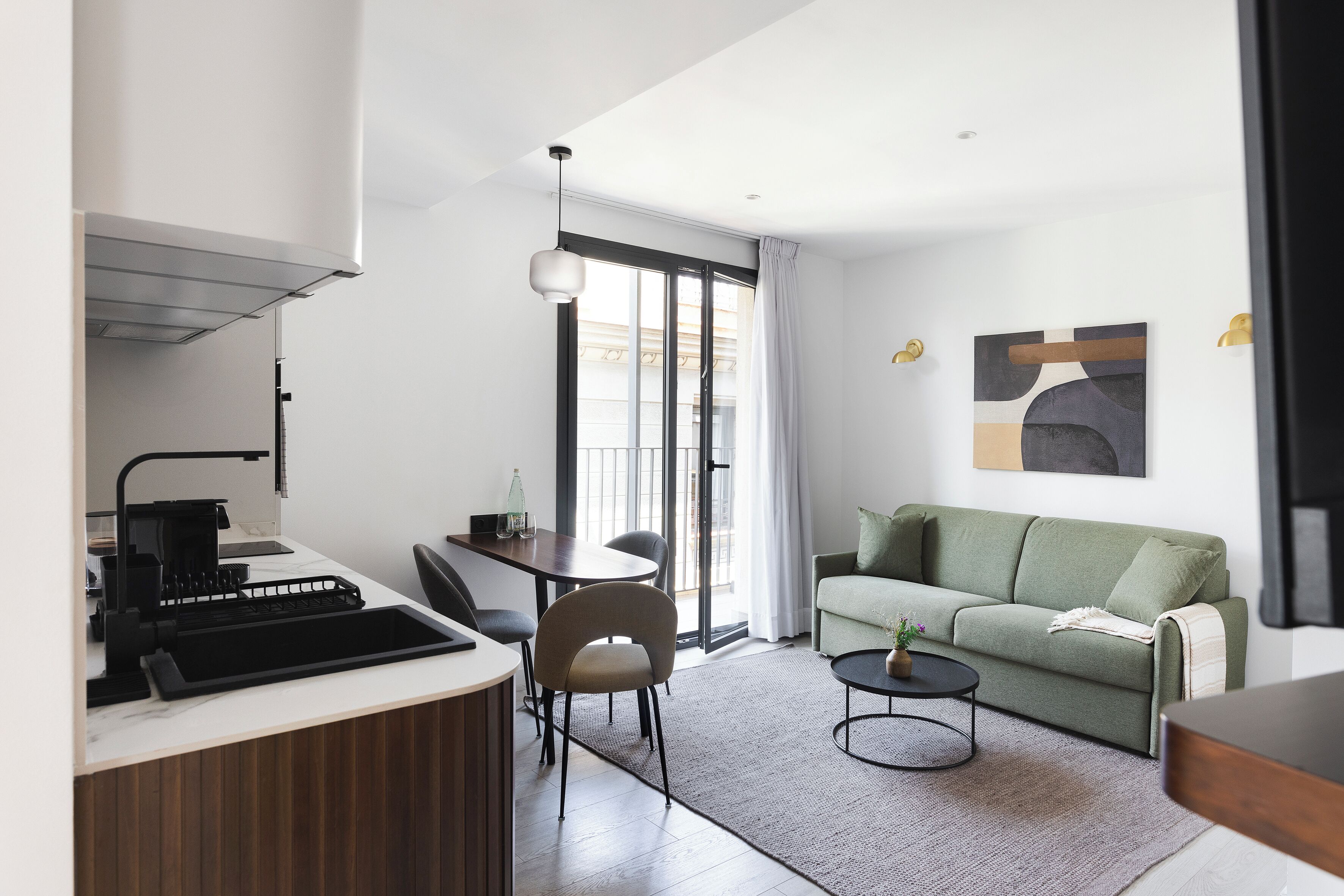 Un salon moderne avec un canapé vert, une table basse et un coin repas comprenant une table et des chaises.