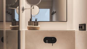 Un baño moderno con un espejo grande, un lavamanos redondo y un pequeño espejo circular sobre el lavamanos.