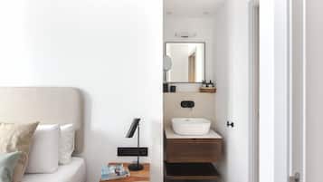A modern bedroom with a bed, bedside table, and a nightstand with a lamp.