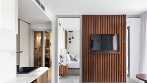 Une chambre à coucher moderne avec une grande télévision, un mur recouvert de panneaux en bois et une table de chevet avec une lampe.