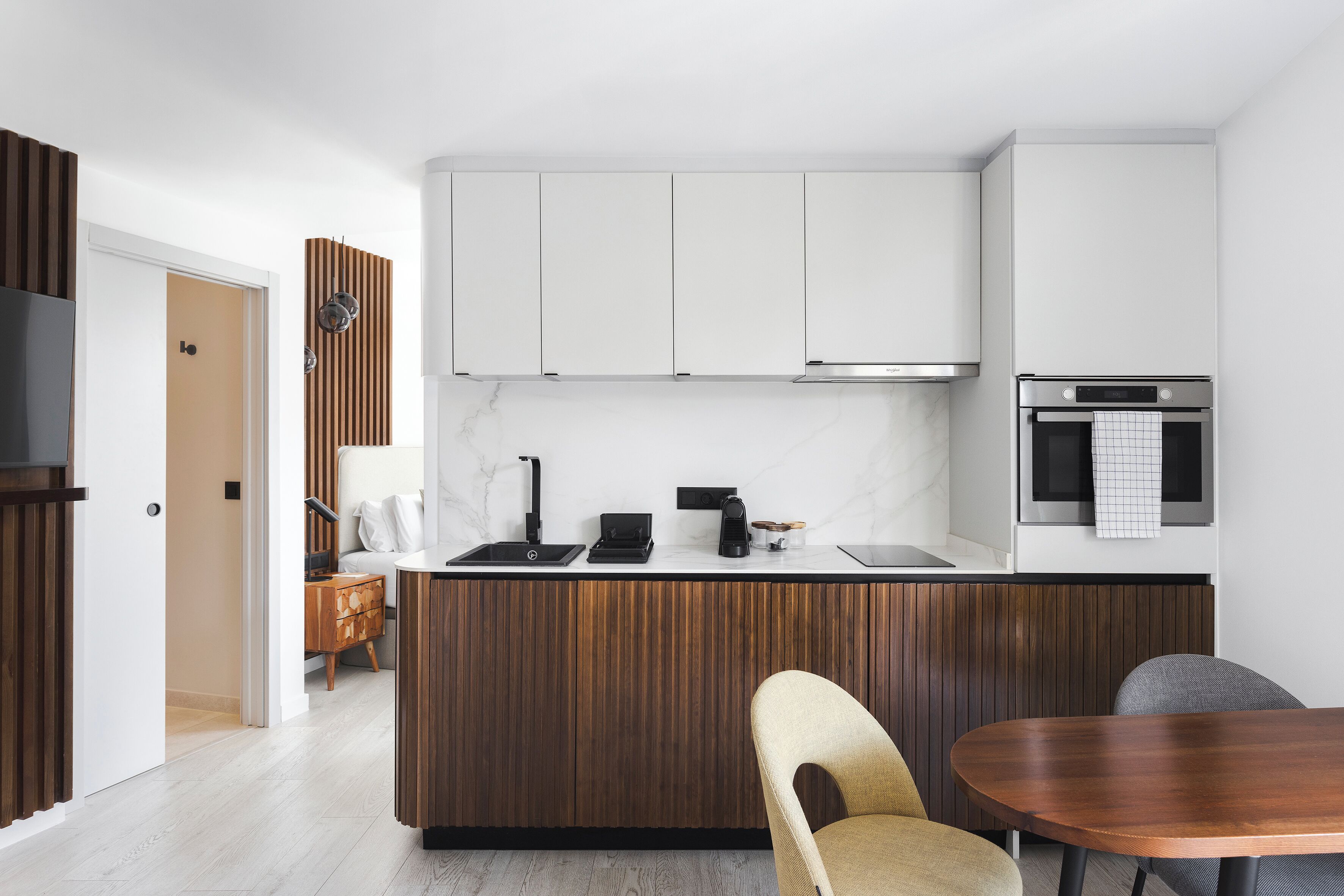 A modern kitchen with a wooden island, white cabinets, and a built-in oven.