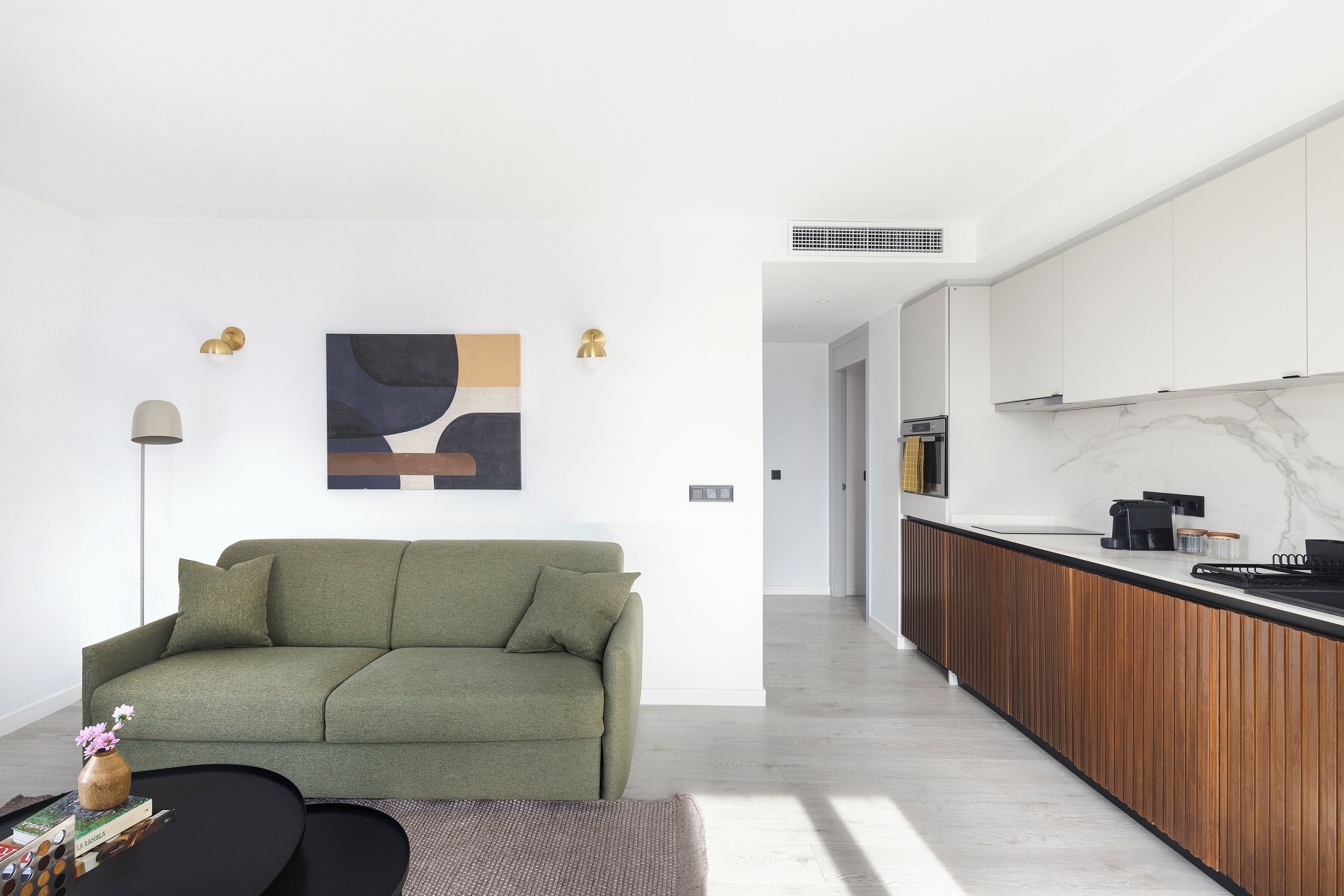 Una sala de estar moderna con un sofá verde, una mesa de centro y un cuadro en la pared.