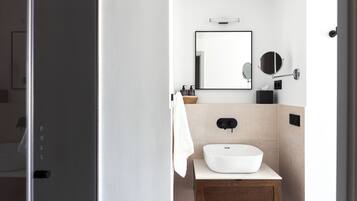 Een moderne badkamer met een witte wastafel, een houten wastafelmeubel en een grote spiegel.