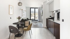 Un appartement moderne comprenant un coin repas, un canapé, une cuisine et offrant une vue sur la ville.