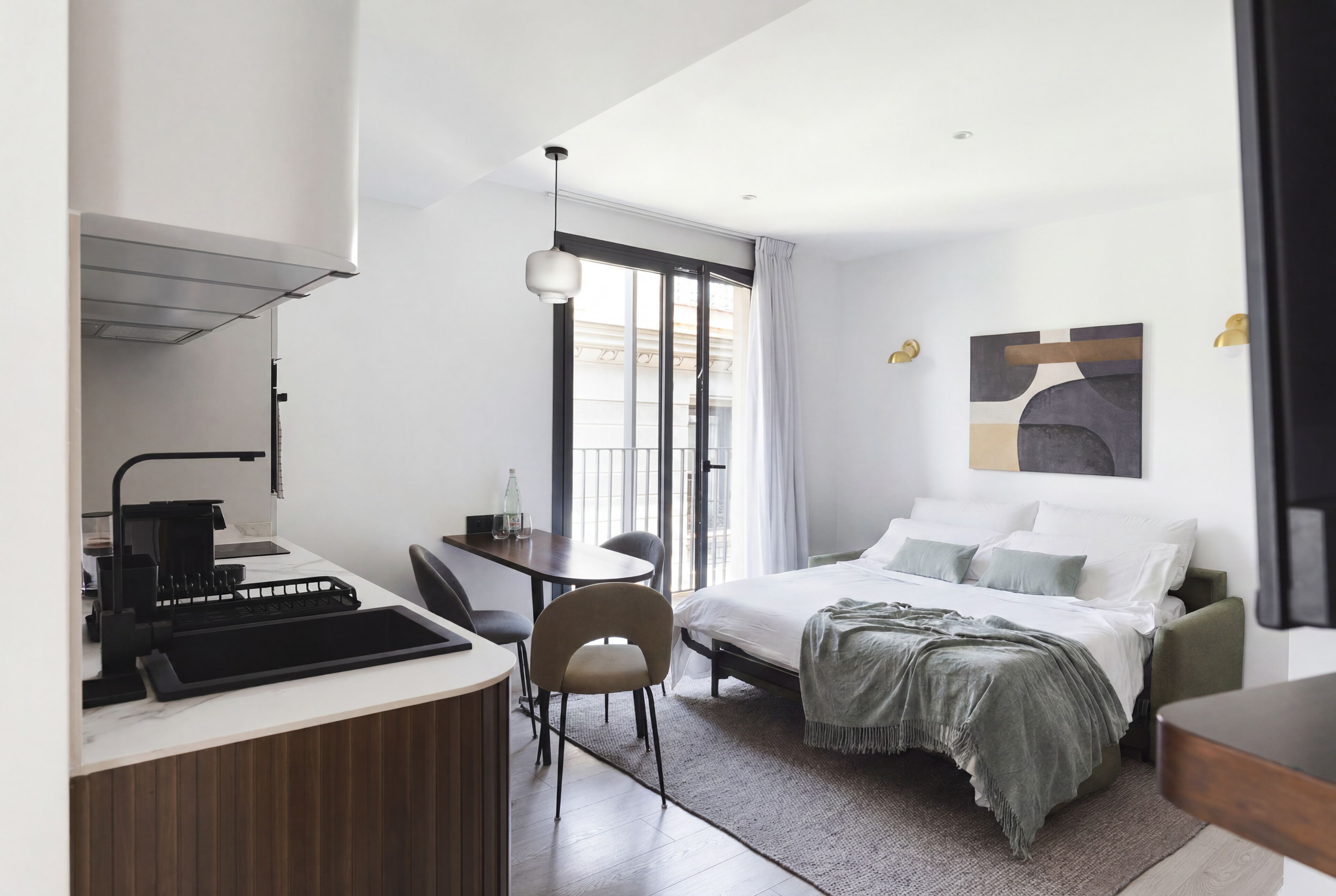 Una habitación de hotel moderna con cama, escritorio, silla y kitchenette.