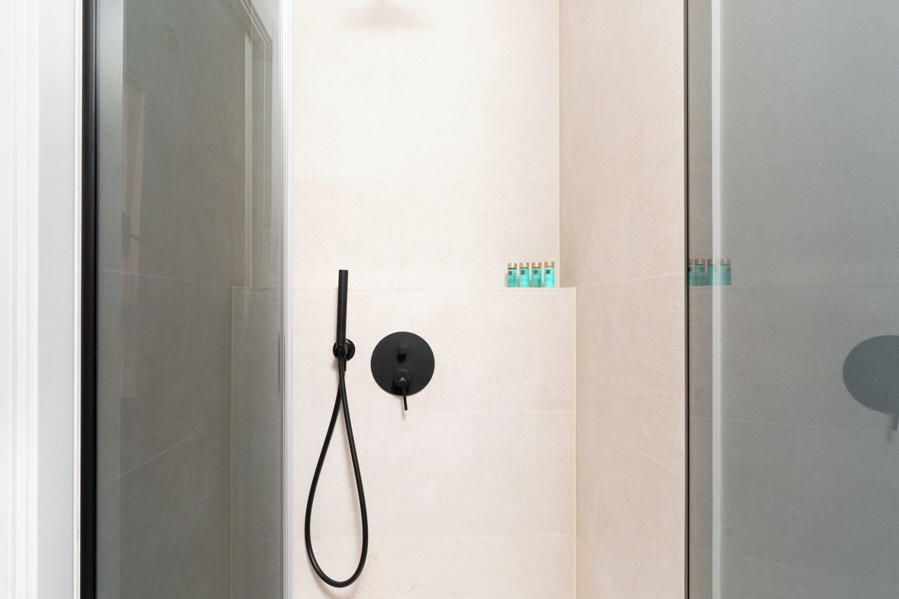 Una ducha con cabezal de ducha de mano y panel de control.