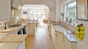 A spacious kitchen with a central island, a dining area with a view, and a large window with a view of greenery. - A family house that sleeps 12 guests  in 6 bedrooms (Bognor Regis)