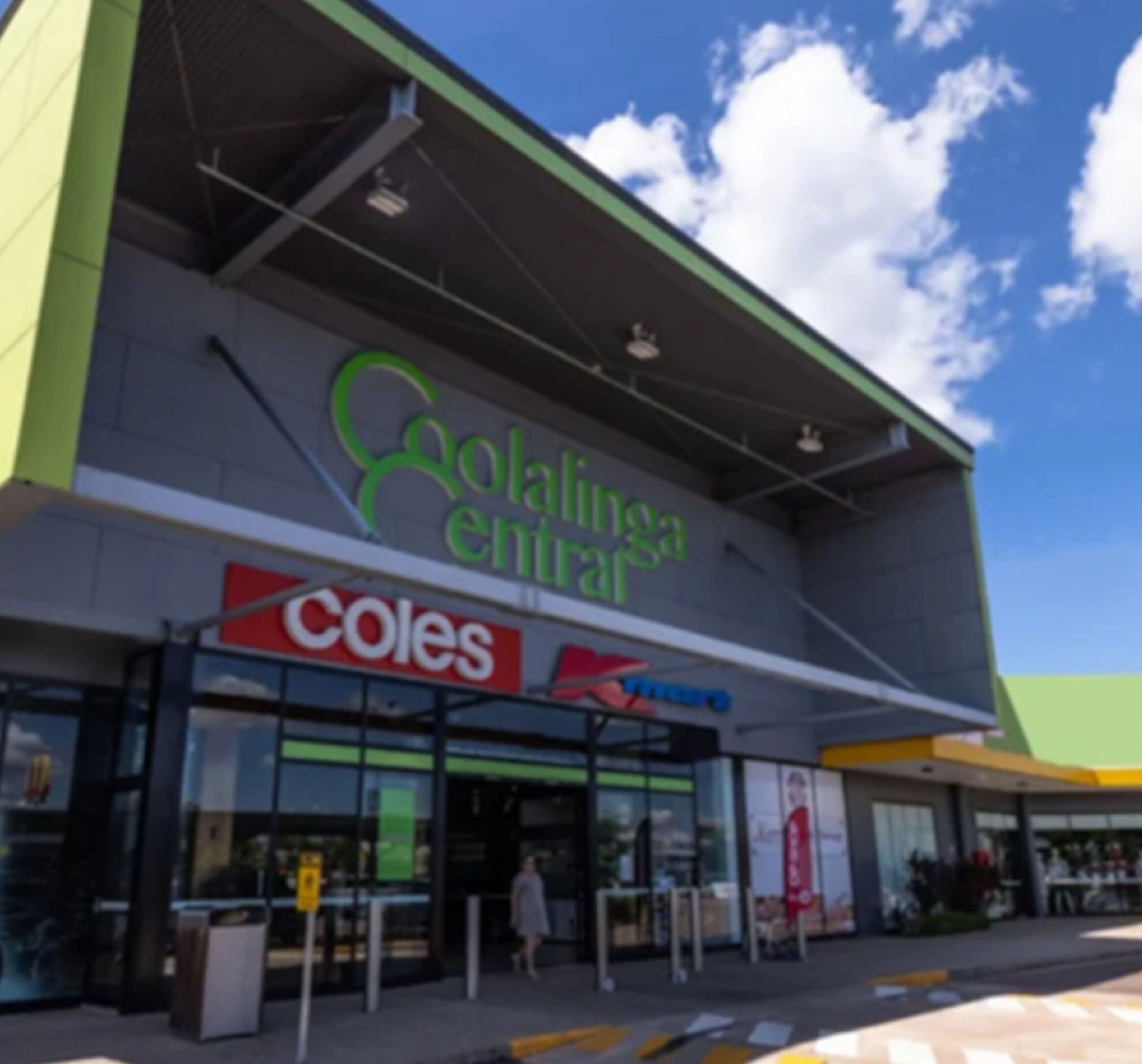 Een gebouw met een gevel in groen en grijs, een duidelijke ingang en borden met 'Coolinga Centre' en 'Coles'.