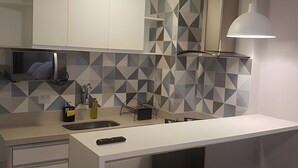 A modern kitchen with a white countertop, a sink, a faucet, and a geometric backsplash. - Studio Copacabana a 100 metros da Praia (Rio de Janeiro)