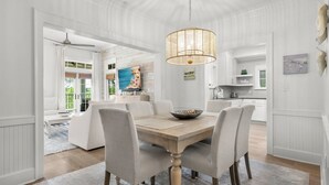 A dining area with a wooden table, six chairs, and a hanging light fixture.
