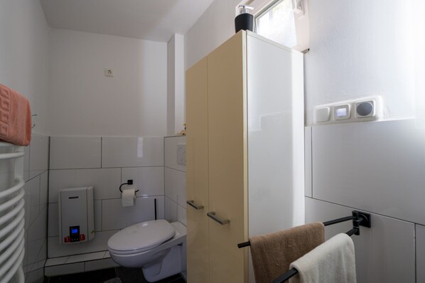 A compact bathroom with a toilet, a towel rack, and a towel hanging on it.