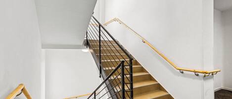 A staircase with a black metal railing and wooden handrails, leading to an upper floor.