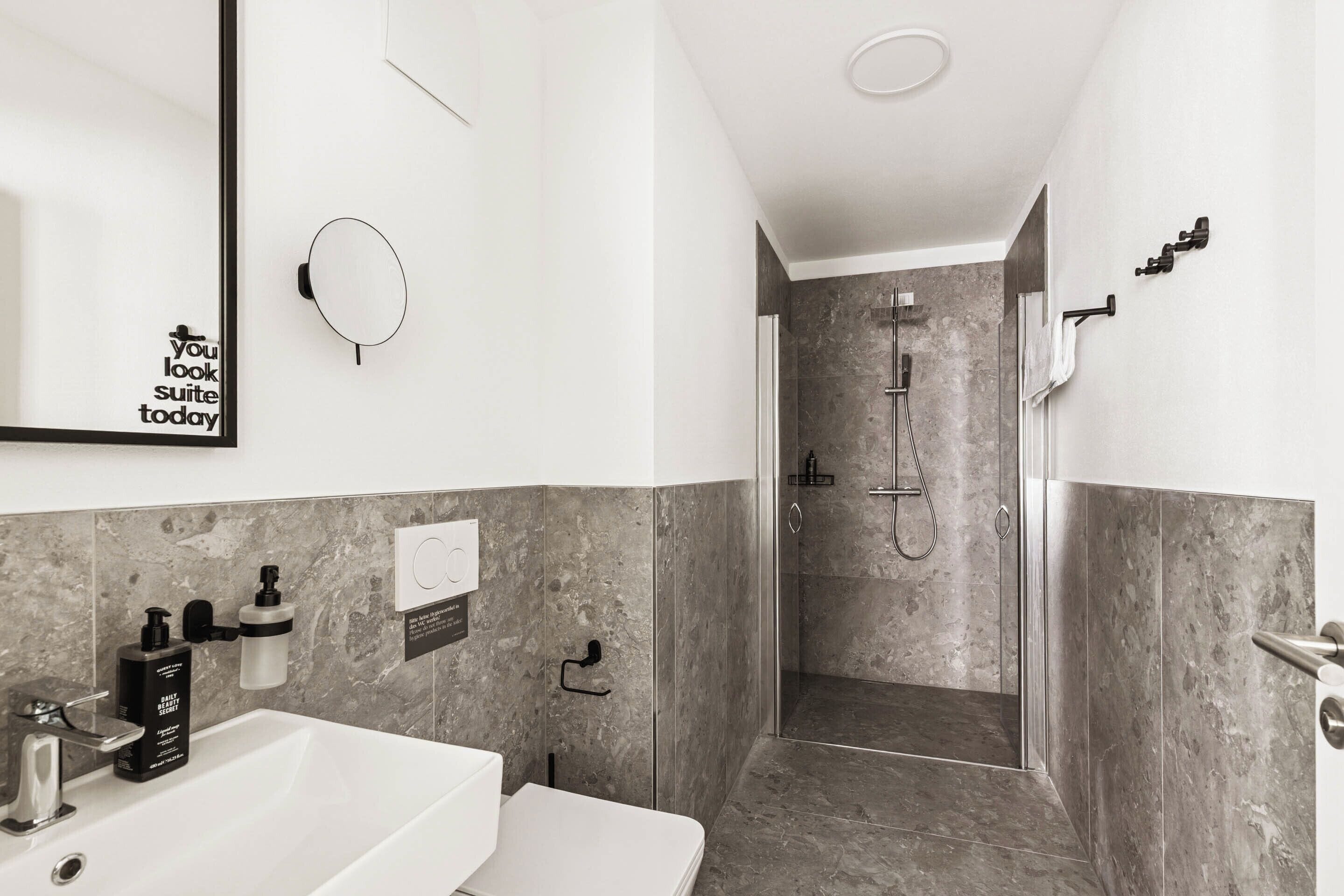 Ein modernes Badezimmer mit einem weißen Waschbecken, einem Spiegel und einer Duschkabine.