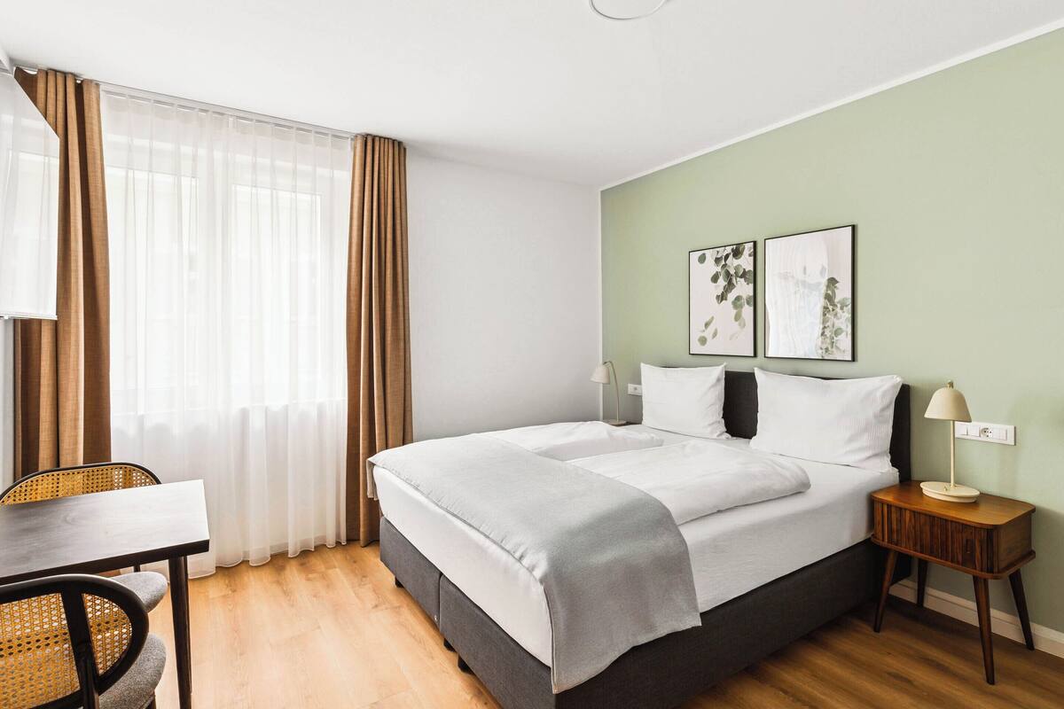 A hotel room with a bed, a desk, and a chair.
