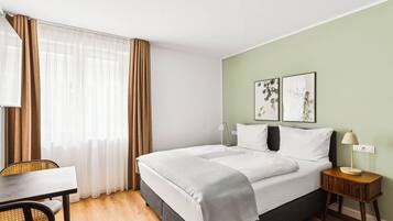 A hotel room with a bed, a desk, and a chair.