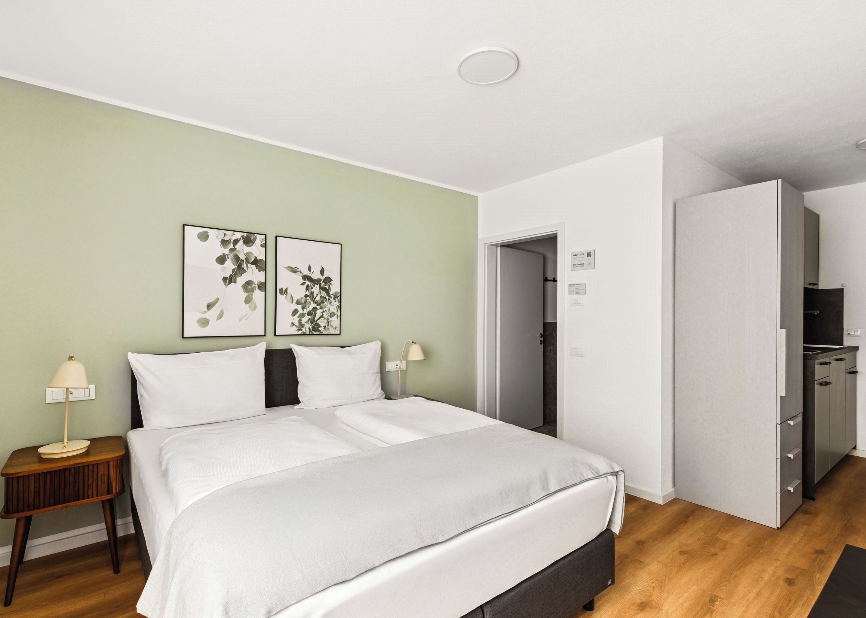 Ein modernes Hotelzimmer mit Bett, Nachttischen und einem Kleiderschrank.
