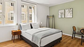 A neatly arranged bedroom with a bed, bedside tables, a chair, and artwork on the wall.