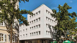 Un edificio moderno con fachada plana, múltiples ventanales y acceso a nivel de calle.