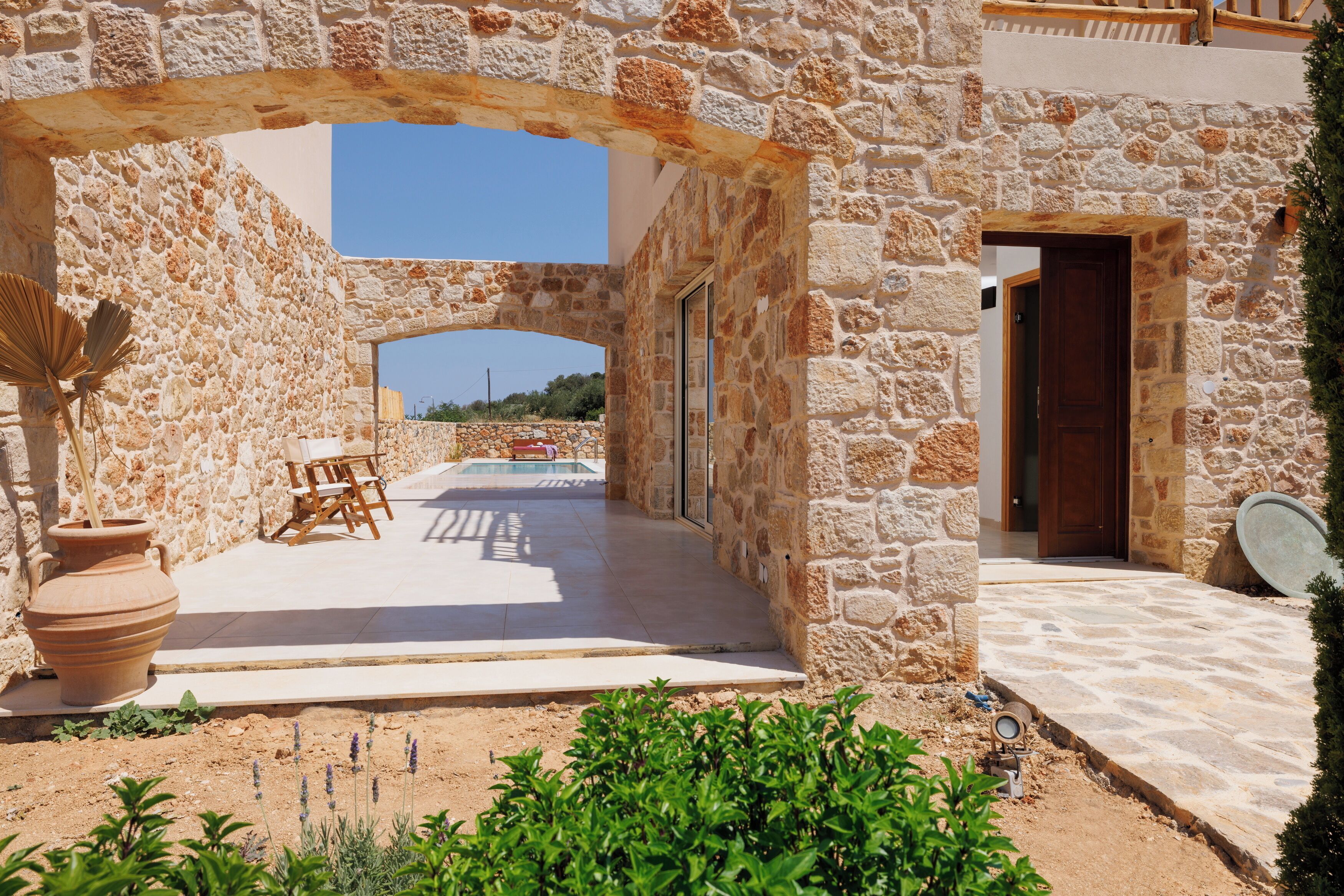 Un edificio de piedra con un patio exterior, piscina y una puerta de entrada.