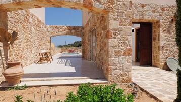 Un edificio de piedra con un patio exterior, piscina y una puerta de entrada.