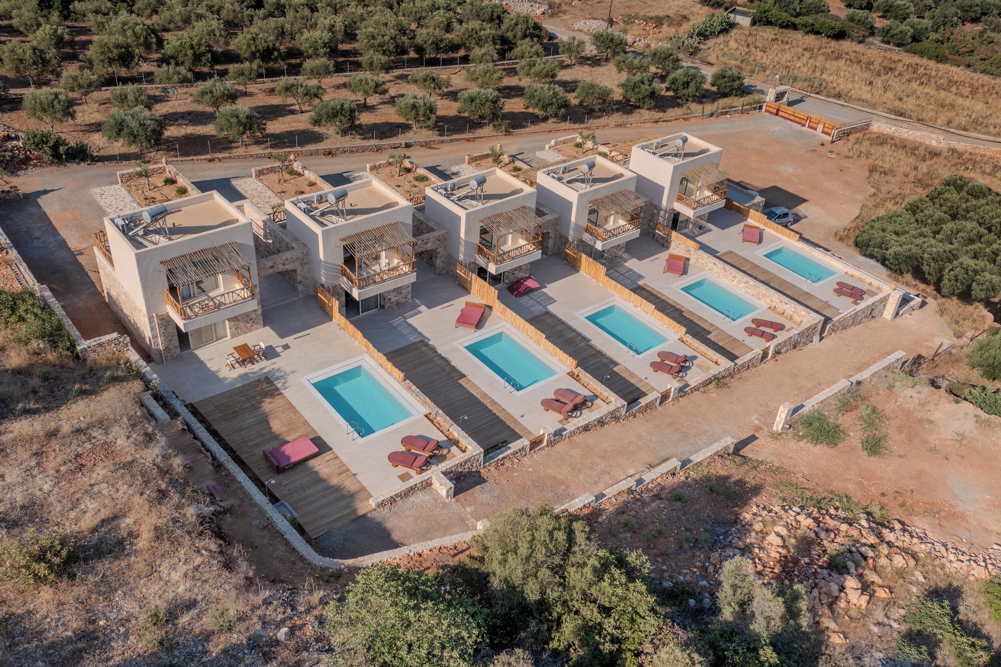 An aerial view of a resort with multiple buildings, each with a pool and outdoor seating.